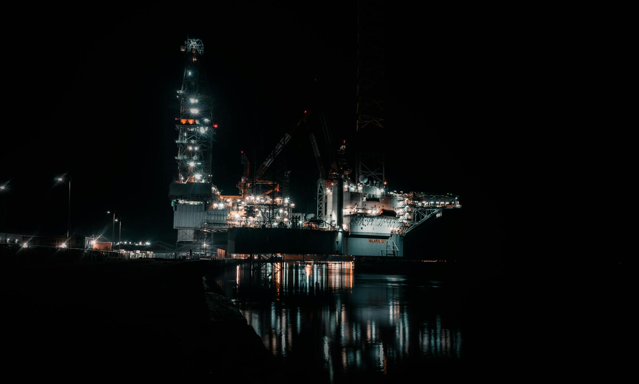 A dramatic offshore oil rig brilliantly lit against the nighttime sky.