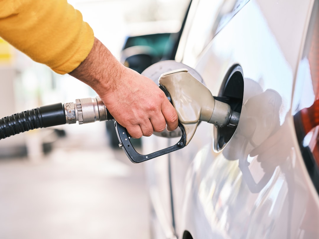 a man pumping gas into his car at a gas station f4ubpvbjcjw